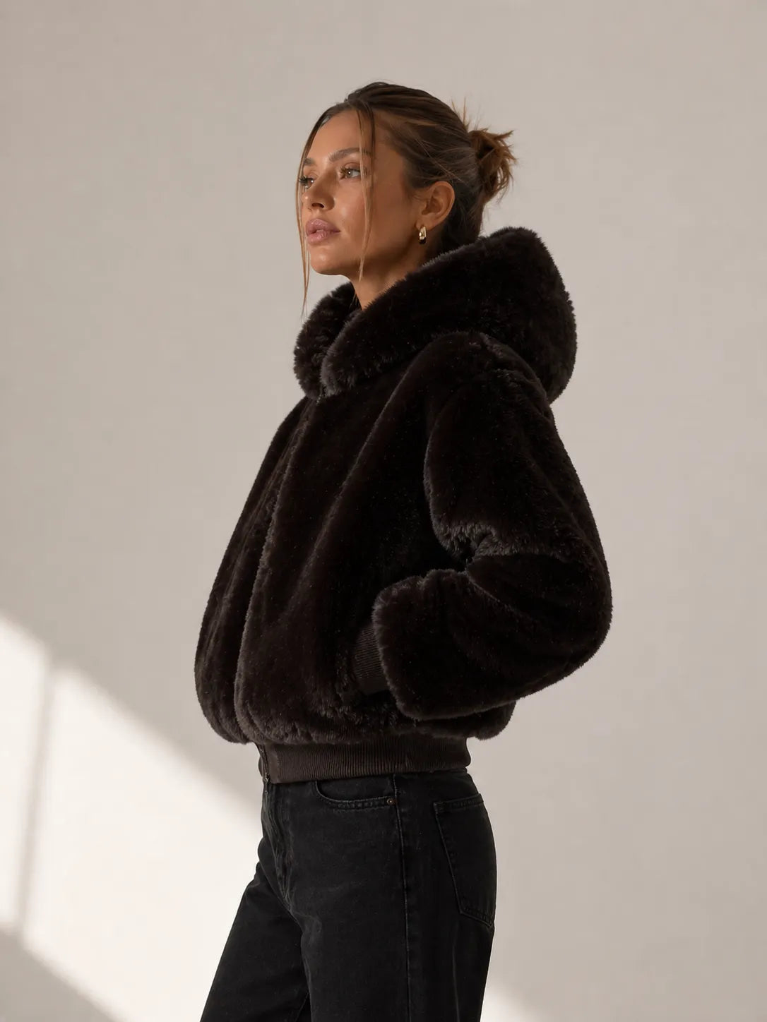 Woman wearing a black fur jacket against a plain background
