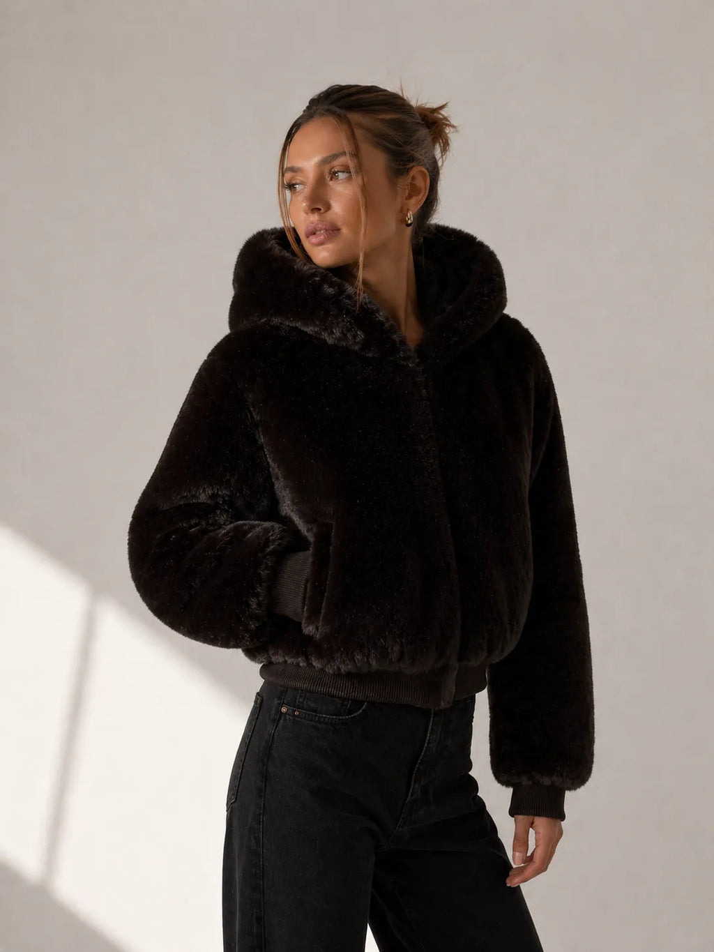 Woman wearing a black fur coat against a plain background