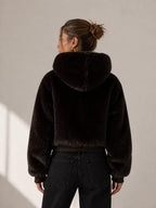 Person wearing a black fur jacket against a neutral background