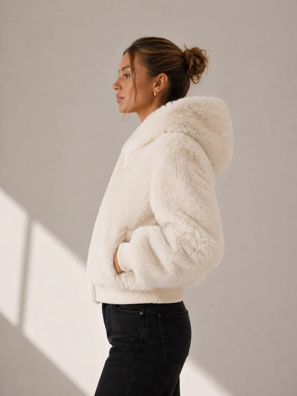Woman wearing a white fluffy jacket against a neutral background