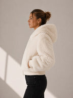 Woman wearing a white fluffy jacket against a neutral background