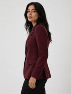 Woman wearing a burgundy blazer against a white background