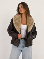 Woman wearing a dark brown leather jacket with fur collar on a white background