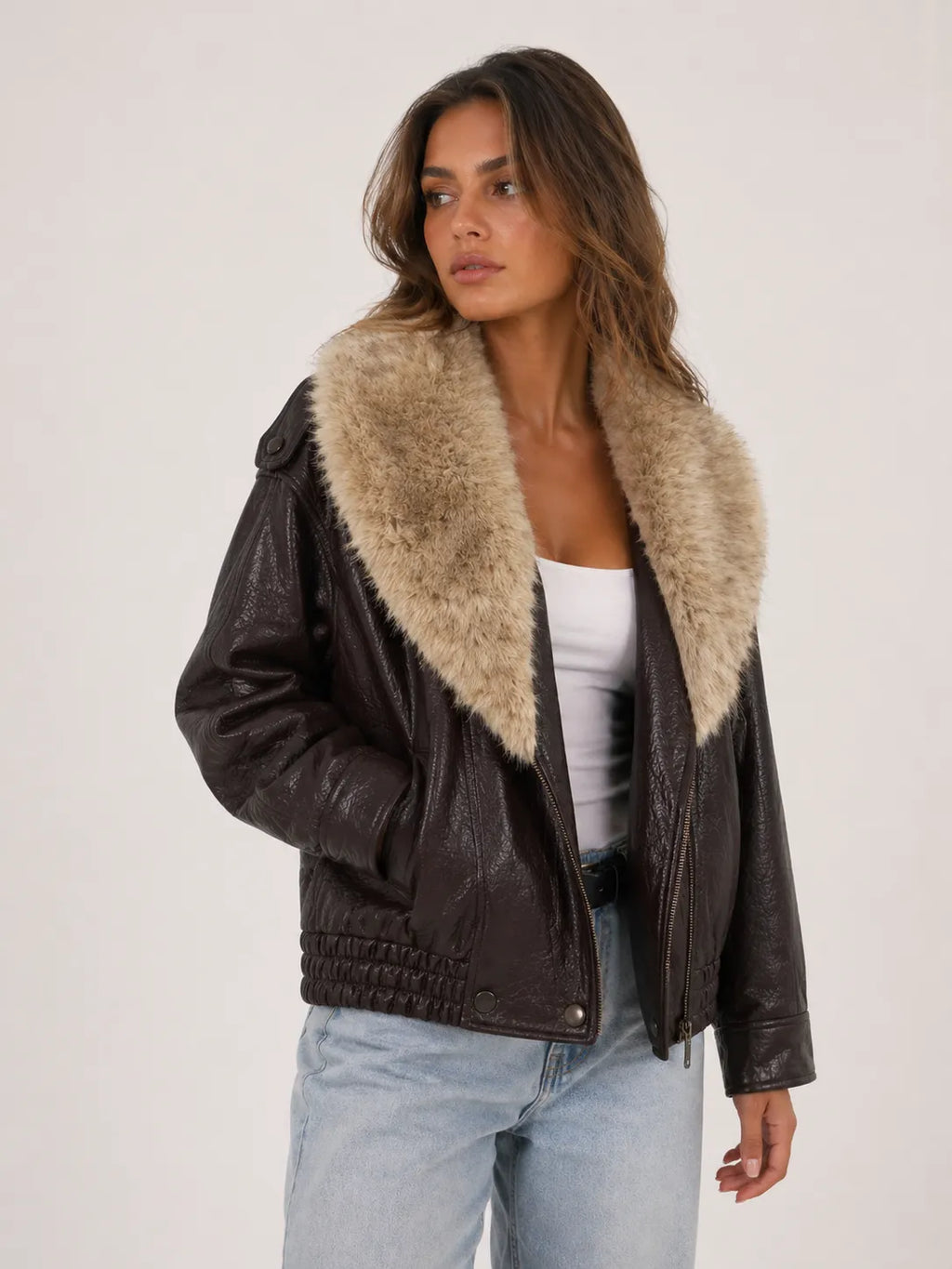 Woman wearing a dark leather jacket with fur collar on a white background