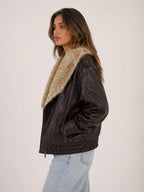 Woman wearing a brown leather jacket with fur lining on a white background