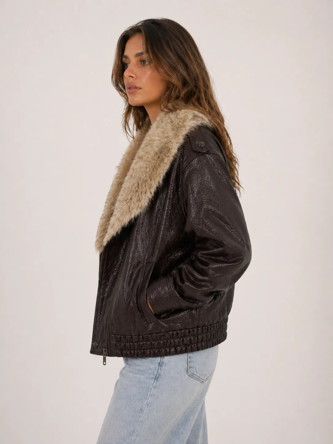Woman wearing a brown leather jacket with fur lining on a white background
