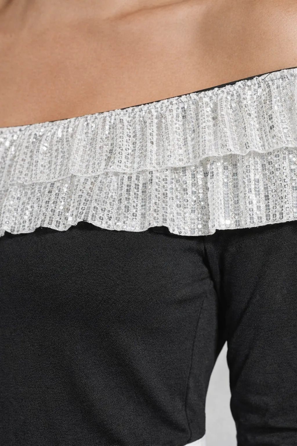 Close-up of a black off-shoulder top with silver sequin trim.
