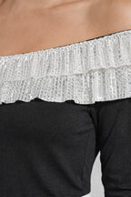 Close-up of a black off-shoulder top with silver sequin trim.