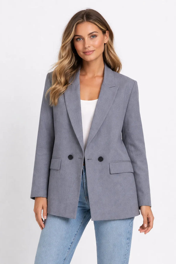 Woman wearing a gray blazer over a white top and blue jeans on a white background