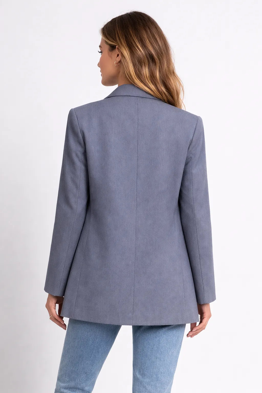 Person wearing a gray blazer and light blue jeans on a white background