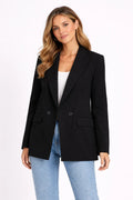Woman wearing a black blazer and light blue jeans on a white background
