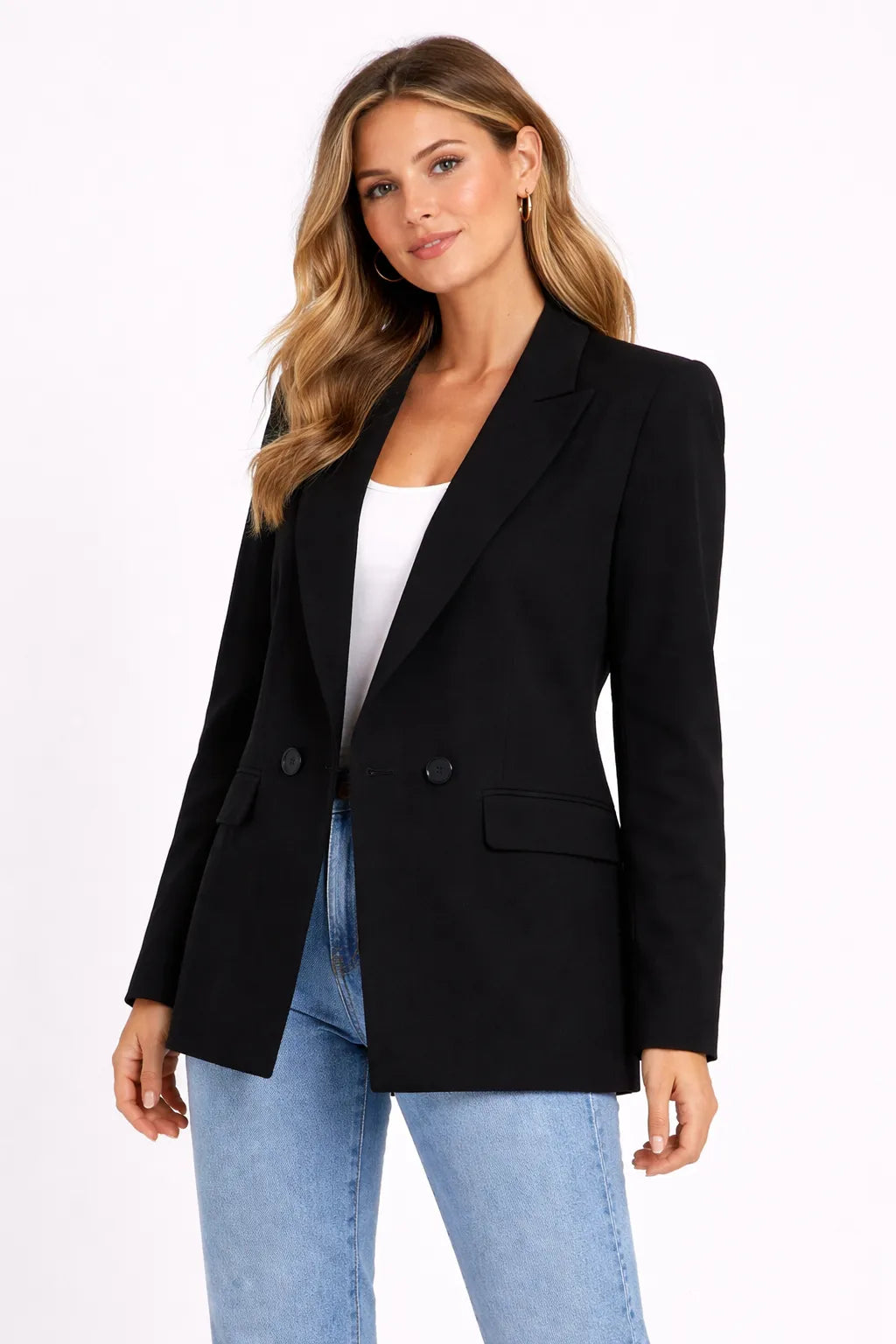 Woman wearing a black blazer over a white top and blue jeans on a white background