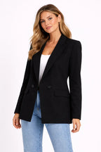 Woman wearing a black blazer over a white top and blue jeans on a white background