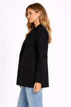 Woman wearing a black blazer and light blue jeans on a white background