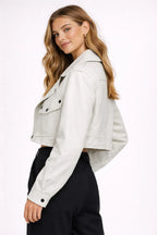 Woman wearing a light gray jacket over a black top on a white background