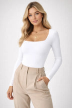 Woman wearing a white long-sleeve top and beige pants on a white background