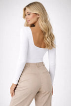 Woman wearing a white long-sleeve top and beige pants on a white background