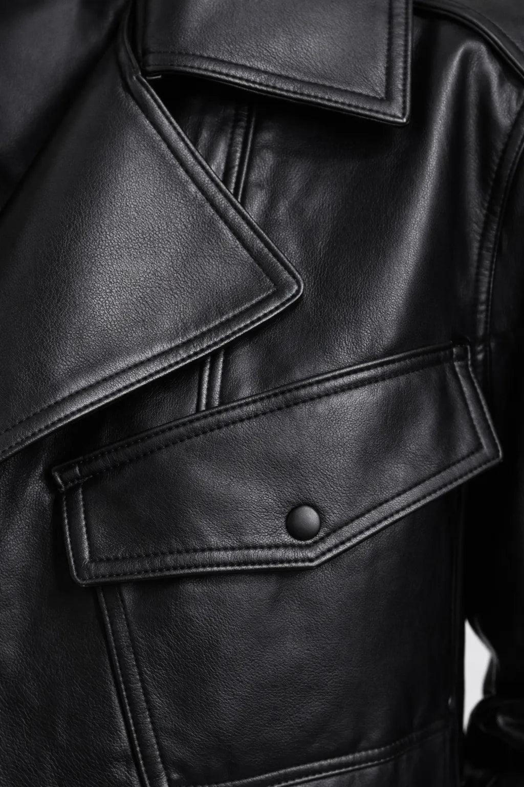 Close-up of a black leather jacket with a button