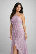 Woman wearing a pink one-shoulder dress with ruffled details on a gray background